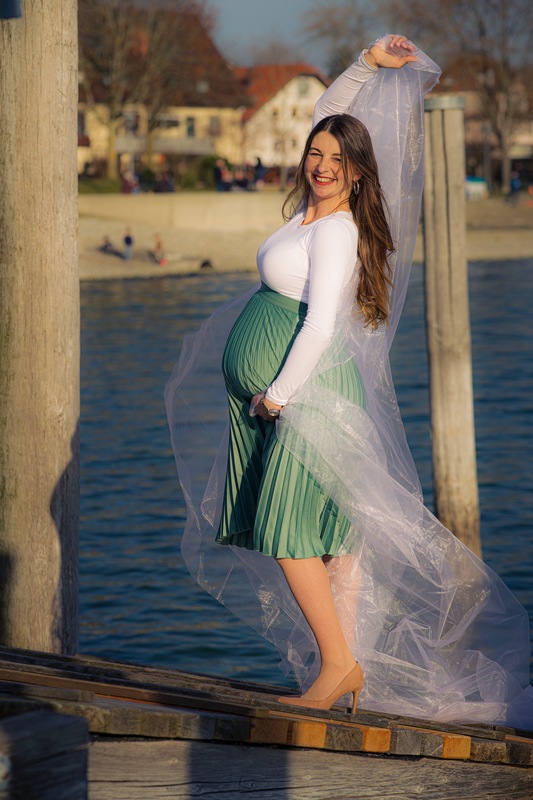 Cooles Babybauchshooting mit wehendem Tuch auf dem Anlegesteg in Allensbach, Bodensee