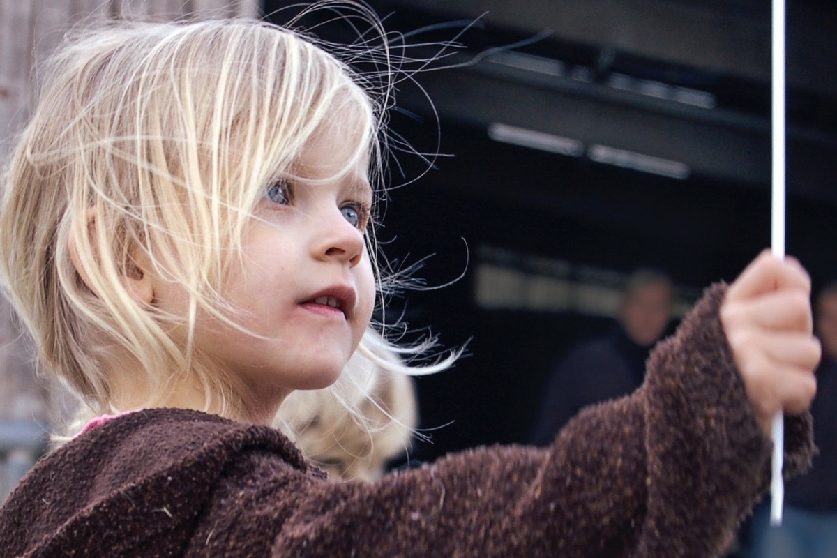 kleines Mdchen mit wehenden Haaren, die nur Augen fr ihre sich drehende Windmhle hat