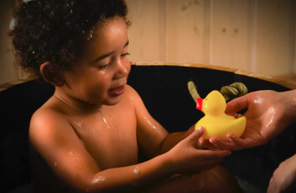 2 jhriger Bub im Badebottich empfngt super sanft die ersehnte gelbe Quitscheente aus der Hand seiner Mama