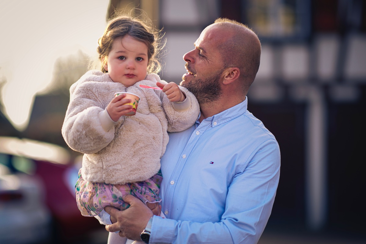 das erste Eis im Jahr - und das schmeckt sooooo gut, ses kleines Mdchen auf Papas Arm Eis essend