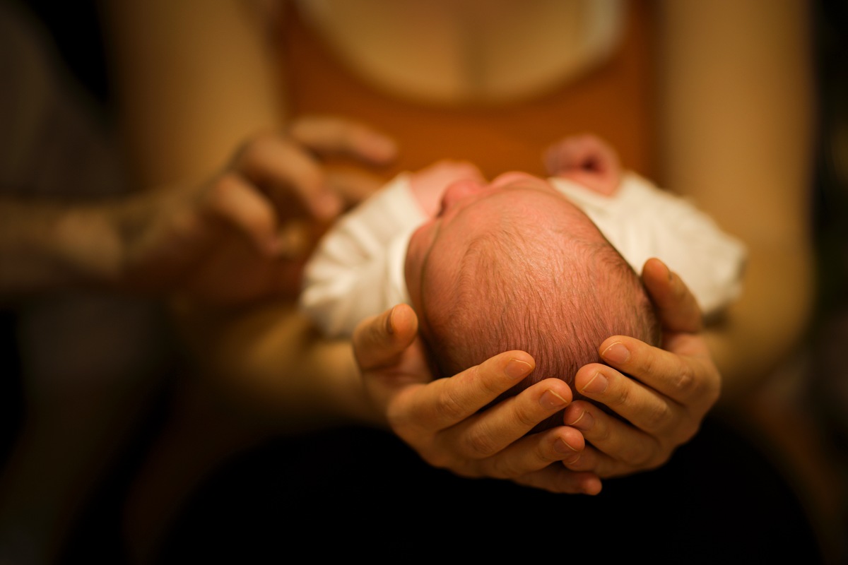 Kpfchen eines 3 Wochen alter Jungen in Mamas schtzenden Hnden