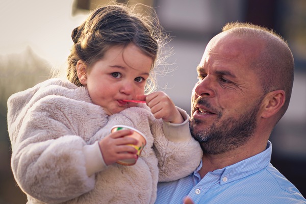 das erste Eis im Jahr - und das schmeckt sooooo gut, s��es kleines M�dchen auf Papa´s Arm Eis essend